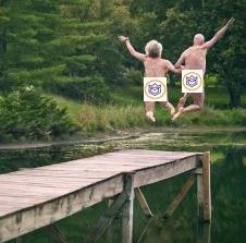 senior couple jumping off dock into pond